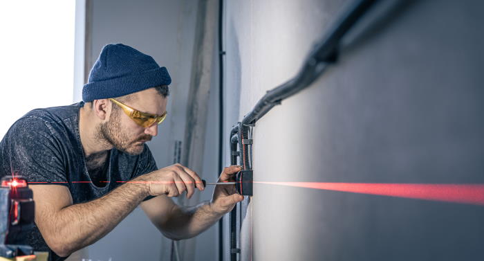 Attractive male electrician repairing an outlet, installing an outlet using laser marking.